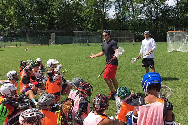 Youth lacrosse players listen to the expert lacrosse staff during a GameBreakers Lacrosse Camp.