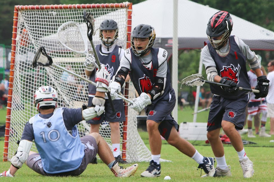 A lacrosse player defends the goal against an attack from an opposing player.