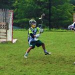 A youth lacrosse player defends the goal from his opponent during a defensive lacrosse drill.