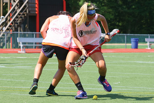 Two players fight for the ground ball during a lax drill at lacrosse camp.